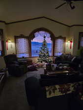 Living area with a ceiling fan, carpet flooring, and lofted ceiling