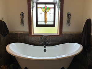 Full bath featuring a soaking tub, tile walls, and wainscoting