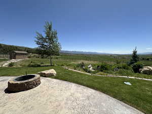View of yard with an outdoor fire pit, a patio, a mountain view, and a view of countryside