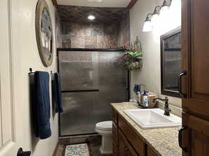 Full bathroom with toilet, a shower stall, vanity, and tile patterned floors