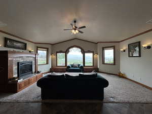Living area featuring vaulted ceiling, ceiling fan, a textured ceiling, baseboards, and a brick fireplace