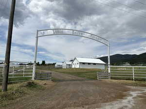 View of dirt / gravel driveway featuring a view of countryside, a mountain view, and a gated entry