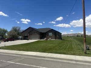 Single story home over basement, with brick siding, concrete driveway, a garage, a front yard, and a mountain view