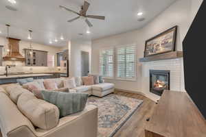Family room with ceiling fan, a fireplace, light wood-style flooring, and recessed lighting