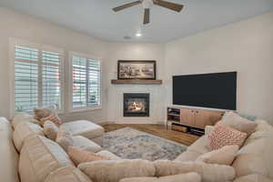 Family room featuring a ceiling fan, recessed lighting, a glass covered fireplace, and wood finished floors