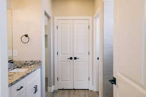 Bathroom featuring a closet, vanity, and wood finished floors