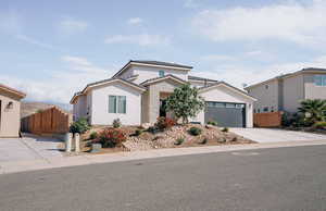 View of front of house with concrete driveway, an attached garage, a tile roof, and stucco siding