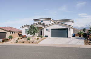 Traditional home featuring a garage, stucco siding, driveway, and a tile roof