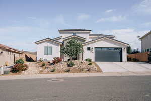 View of front of home with an attached garage, stucco siding, concrete driveway, and a tiled roof