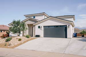 View of front facade with a garage, concrete driveway, stucco siding, and stone siding