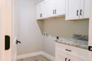 Laundry room featuring hookup for a washing machine, light wood-style flooring, cabinet space, hookup for an electric dryer, and baseboards
