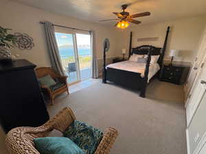 Bedroom featuring access to exterior, carpet floors, ceiling fan, a textured ceiling, and a water view