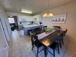 Dining room featuring a chandelier, a textured ceiling, light tile patterned floors, and baseboards