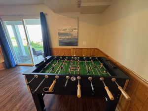 Game room with a wainscoted wall, wood finished floors, and wood walls