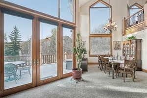 Doorway to outside with carpet, a chandelier, a towering ceiling, and baseboards