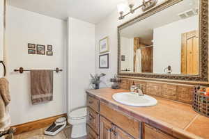 Bathroom with vanity, toilet, curtained shower, tile patterned flooring, and baseboards