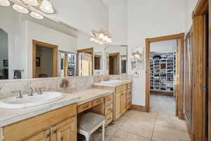 Bathroom featuring double vanity, a spacious closet, tile patterned flooring, and tasteful backsplash