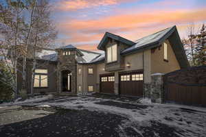 View of front of house featuring stone siding, driveway, stucco siding, and a gate