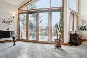 Doorway featuring carpet flooring, baseboards, a high ceiling, and french doors