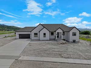 Modern farmhouse featuring a mountain view, a garage, concrete driveway, stucco siding, and roof with shingles