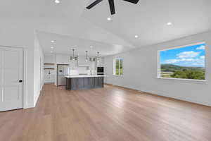Kitchen featuring refrigerator with ice dispenser, light countertops, vaulted ceiling, white cabinets, and ceiling fan