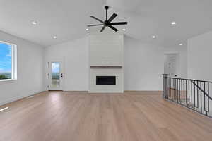 Unfurnished living room with light wood finished floors, ceiling fan, recessed lighting, baseboards, and a large fireplace