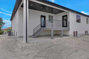 Back of house featuring stucco siding, central air condition unit, and a patio area