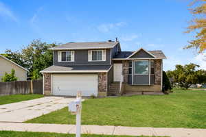 Tri-level home with an attached garage, brick siding, and concrete driveway