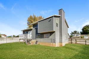 Back of house with a fenced backyard, a chimney, and stairs