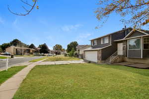 View of green lawn with driveway, a garage, and a residential view