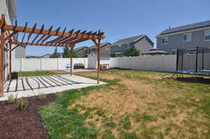 View of yard with a trampoline, a patio, a residential view, and a pergola