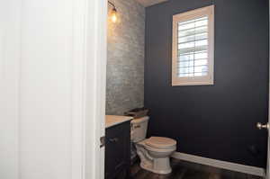 Half bath featuring toilet, wood finished floors, and vanity