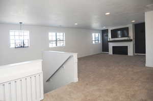 Unfurnished living room featuring carpet floors, recessed lighting, a large fireplace, baseboards, and a chandelier