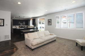 Living room with recessed lighting, baseboards, and dark wood-style floors