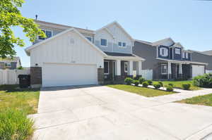 View of front of house with board and batten siding, concrete driveway, an attached garage, and stone siding