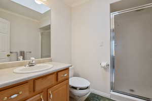 Full bathroom with toilet, a stall shower, crown molding, vanity, and baseboards