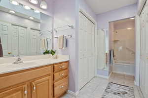 Bathroom featuring a closet, vanity, tile patterned floors, tub / shower combination, and baseboards