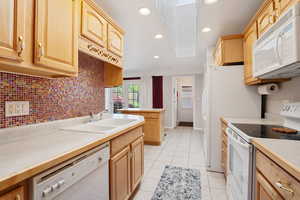 Kitchen featuring white appliances, a sink, light tile patterned floors, light brown cabinets, and recessed lighting