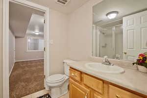 Bathroom featuring a stall shower, vanity, toilet, tile patterned flooring, and baseboards