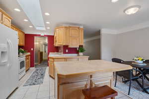 Kitchen with white appliances, light brown cabinetry, a sink, light countertops, and recessed lighting