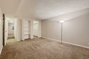 Unfurnished bedroom with carpet flooring, a textured ceiling, and baseboards