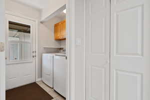 Washroom featuring cabinet space, independent washer and dryer, and light tile patterned floors