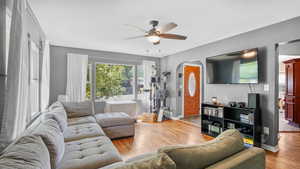 Living room featuring ceiling fan, arched walkways, wood finished floors, and baseboards