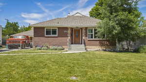 Bungalow-style house featuring a gate, brick siding, and a shingled roof