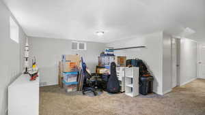 Carpeted office featuring a textured ceiling and baseboards