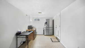 Office with a textured ceiling, light tile patterned flooring, and baseboards