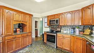 Kitchen featuring stainless steel appliances, tasteful backsplash, and brown cabinetry