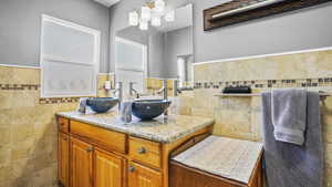 Bathroom with tile walls, vanity, and a wainscoted wall