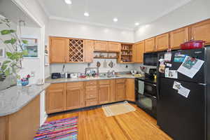 Kitchen featuring black appliances, open shelves, a sink, light wood finished floors, and ornamental molding