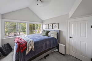 Bedroom with carpet flooring, vaulted ceiling, multiple windows, and ceiling fan